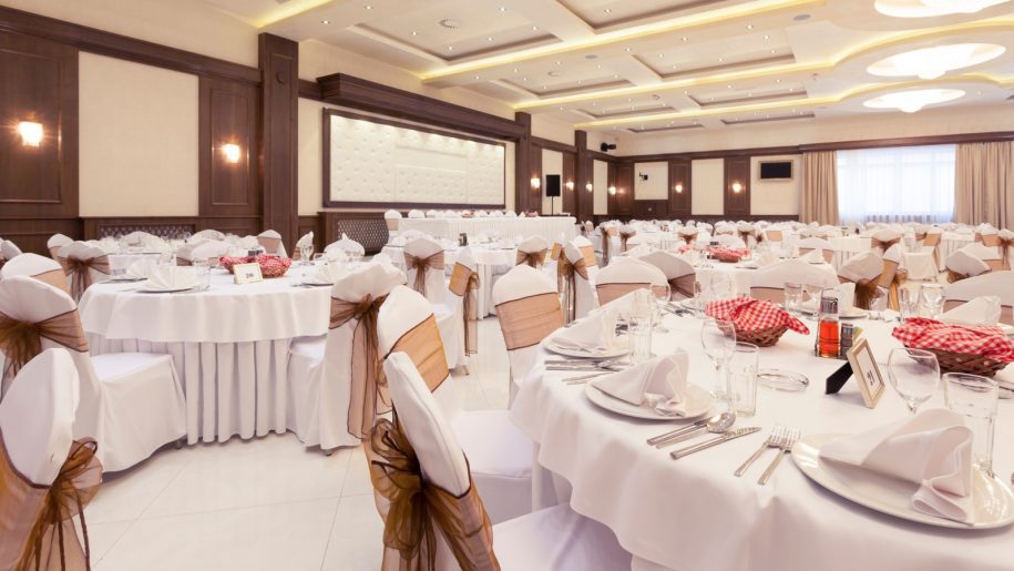 White chairs and tables in a fancy banquet hall of Hotel Hari's Court for a corporate event