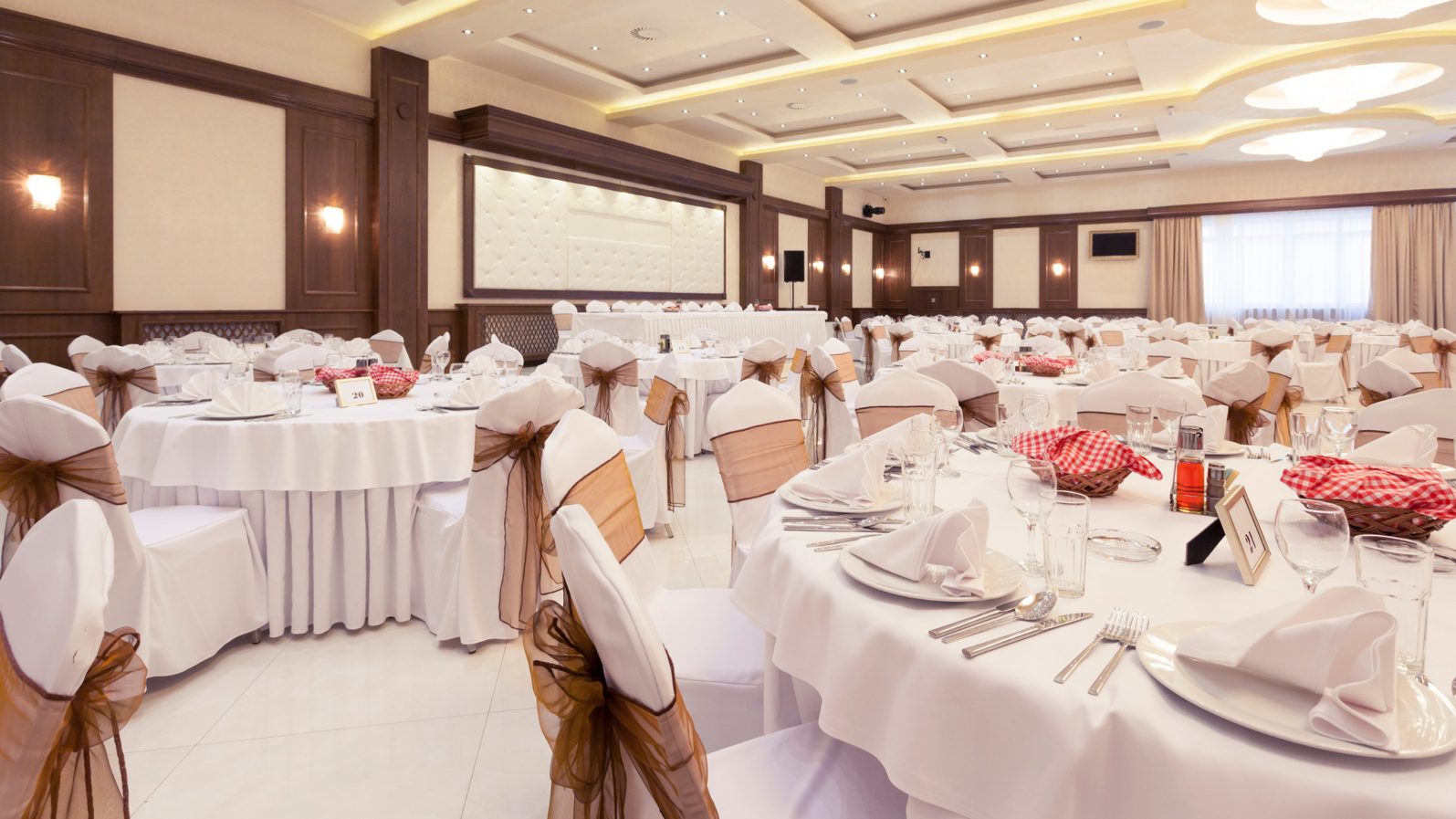 White chairs and tables in a fancy banquet hall of Hotel Hari's Court for a corporate event